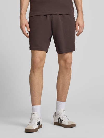 Männermodel trägt Regular Fit Sweatshorts mit Baumwoll-Anteil von adidas Originals, Optik: Unifarben, Waffelstruktur, Logo-Stitching, Tunnelzug innen, Bundabschluss: elastisch, seitliche Eingrifftaschen, Ganzkörperansicht von vorne.