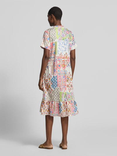 Frauenmodel trägt Midikleid mit V-Ausschnitt und seitlicher Schnürung von Smith and Soul aus reiner Baumwolle im Allover-Look, A-Linie, bunte Muster, fließender Stoff, Ganzkörperansicht Rückansicht.