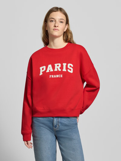 Frauenmodel trägt Oversized Sweatshirt aus Baumwoll-Mix Modell 'SWEAT LIFE' von Only in Rot mit Motiv-Print, unifarben, Ganzkörperansicht von vorne.