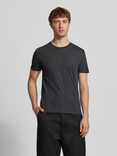Männermodel trägt Slim Fit T-Shirt aus Baumwoll-Mix Modell 'JASPE HERITAGE' von Tommy Jeans in Melange-Optik, Logo-Stitching, Kurzarm, Ganzkörperansicht von vorne.