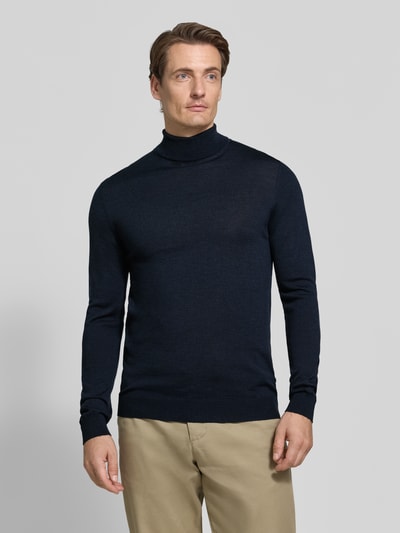Männermodel trägt Slim Fit Rollkragenpullover aus reiner Baumwolle von Matinique in Dunkelblau, glatte Textur, Ganzkörperansicht von vorne.