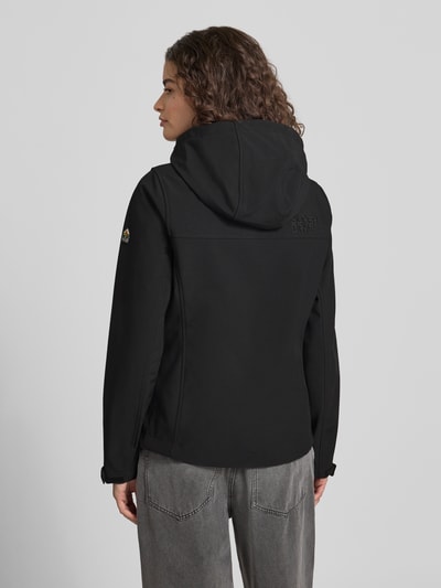 Frauenmodel trägt Trekker Jacke mit Kapuze und Label-Patch von Superdry in Schwarz, Material-Mix mit Stretch-Anteil, Gerader-Schnitt, verstellbare Ärmelriegel mit Klettverschluss, Reißverschluss, seitliche Reißverschlusstaschen, Rückansicht, Ganzkörperansicht Rückansicht.