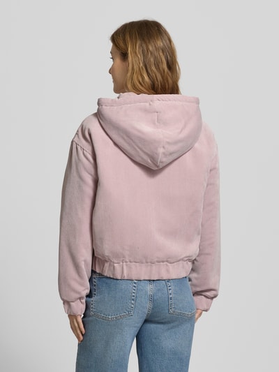 Frauenmodel trägt Regular Fit Bomberjacke mit Kapuze Modell 'SUVA' von Only, rosa Cord, unifarben, gestreift, elastische Abschlüsse, Ganzkörperansicht Rückansicht.
