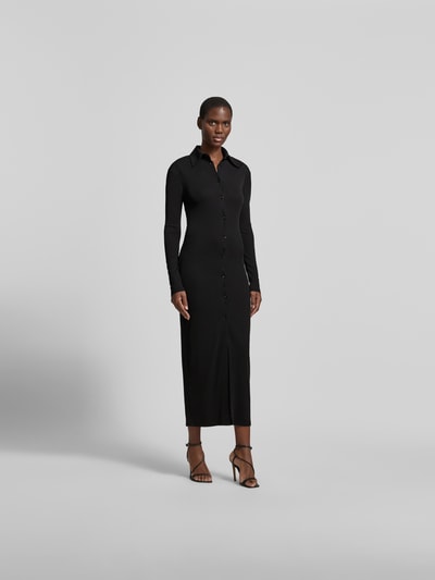 Frauenmodel trägt eng anliegendes Hemdblusenkleid in Maxilänge von Nanushka in Schwarz, Hemdblusenkragen, durchgehende Knopfleiste, langärmelig, Ganzkörperansicht von vorne.