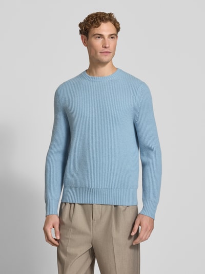 Männermodel trägt Strickpullover aus Kaschmir mit Rundhalsausschnitt von FTC Cashmere in Hellblau, grob gestrickt, Ganzkörperansicht von vorne. Rückenlänge 68 cm, Ärmellänge 72 cm, gerader Schnitt, gerippter Rundhalsausschnitt.