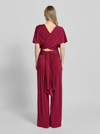 Vrouwenmodel draagt Jumpsuit mit rückseitig gekreuzten Trägern van Rose Avenue in bordeaux, regular fit, diepe V-hals, ruches, ruglengte 120 cm, borstwijdte 50 cm, totale lengte 120 cm, binnenbeenlengte 92 cm, volledige lichaamsopname achterkant