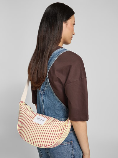 Frauenmodel trägt Bauchtasche mit Logo-Patch Modell 'Poplin' von STUDIO NOOS, gestreifte Farben, Hauptfach mit Reißverschluss, Schulterriemen, Damen, Ganzkörperansicht Rückansicht. Breite: 41 cm, Länge: 21 cm, Tiefe: 10 cm, Länge Schulterriemen: 63 cm.