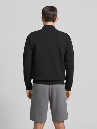 Männermodel trägt Sweatjacke mit Reißverschluss von EA7 Emporio Armani in Schwarz, Herren, Regular-Fit, Gerippte-Abschlüsse, Stehkragen, Rückenlänge 70 cm, Ärmellänge 66 cm, Eingrifftaschen, Label-Detail, Ganzkörperansicht Rückansicht.