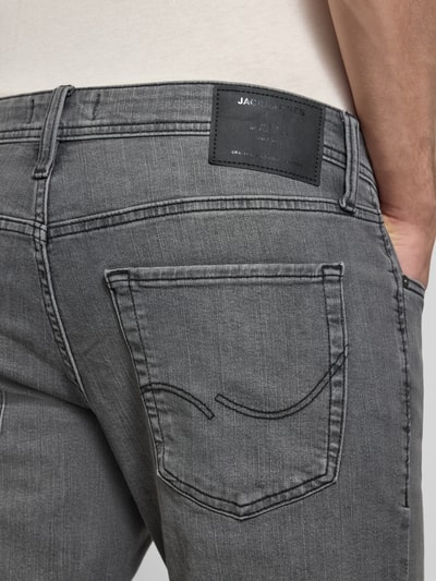 Männermodel trägt Straight Fit Jeans im 5-pocketmodel Model 'GLENN' van JACK & JONES in grijs katoenmix met stretch, detailaufnahme achterzak.