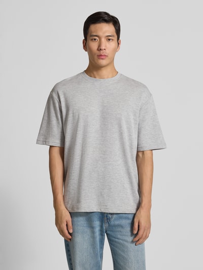 Männermodel trägt Oversized Shirt aus Baumwoll-Mix Modell 'LOOSEOSCAR' von SELECTED HOMME in Melange Unifarben mit Label-Stitching, Rundhals und Kurzarm, Feinripp-Textur, Passform: Oversized, Ganzkörperansicht von vorne.
