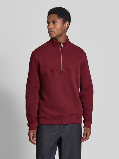 Männermodel trägt Regular Fit Troyer aus reiner Baumwolle Modell 'WAARLO' von ARMEDANGELS in Dunkelrot, glatte Textur, Ganzkörperansicht von vorne.