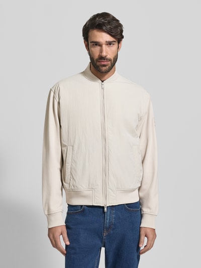 Männermodel trägt Regular Fit Bomberjacke mit Baumwoll-Anteil Modell 'ZE_SMARTCORE' van BOSS Orange, uni crème, college-kraag, lange mouwen, geribde boorden, steekzakken; ganzkörperansicht von vorne.