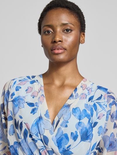 Frauenmodel trägt Midikleid im Allover-Look mit Bindegürtel von ZABAIONE mit V-Ausschnitt in Blau- und Rosatönen, Nahaufnahme Oberkörper. Modell Mo44moo, A-Linie, semi-transparente Textur.