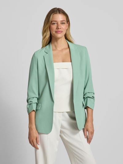 Frauenmodel trägt Regular Fit Blazer mit Reverskragen von Jake*s Collection in Mintgrün, glatte Textur, Pattentaschen, Ganzkörperansicht von vorne. Elastischer Material-Mix, Rückenlänge 69 cm, Brustweite 46 cm, Ärmellänge 52 cm bei Größe 36.