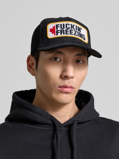 Männermodel trägt Basecap mit Label-Detail von Dsquared2 in Schwarz aus reiner Baumwolle, Nahaufnahme Oberkörper. Verstärkter Schirm, verstellbarer Verschluss, eingestickte Luftlöcher.