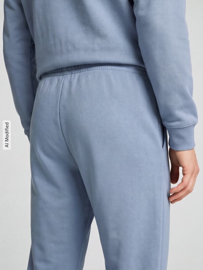 Männermodel trägt hellblaue Jogginghose mit glatter Textur, Detailaufnahme Rückansicht, KI-modifiziertes Bild.