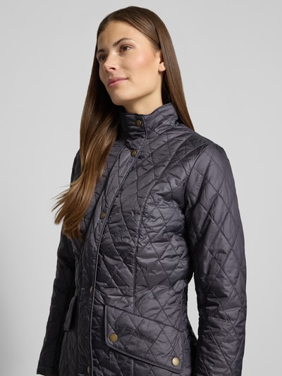 Frauenmodel trägt Regular Fit Steppjacke mit Stehkragen Modell 'FLYWEIGHT' von Barbour in Unifarben, Nahaufnahme Oberkörper.