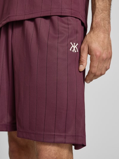 Männermodel trägt Shorts mit elastischem Bund Modell 'Insignia Shadow' von KARL KANI, relaxter Schnitt, Streifenmuster, Nahaufnahme Oberschenkel.