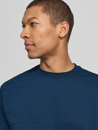 Männermodel trägt T-Shirt mit Rundhalsausschnitt von Scotch & Soda in Dunkelblau, Baumwoll-Elasthan-Mix, Nahaufnahme Oberkörper.