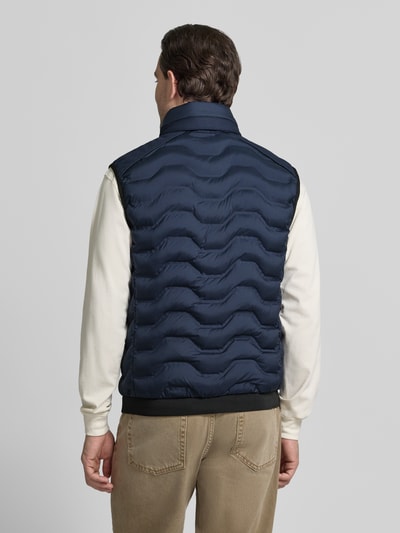 Männermodel trägt Regular Fit Steppweste mit Kapuze im Kragen von Tom Tailor in Dunkelblau, unifarben, Ganzkörperansicht Rückansicht.