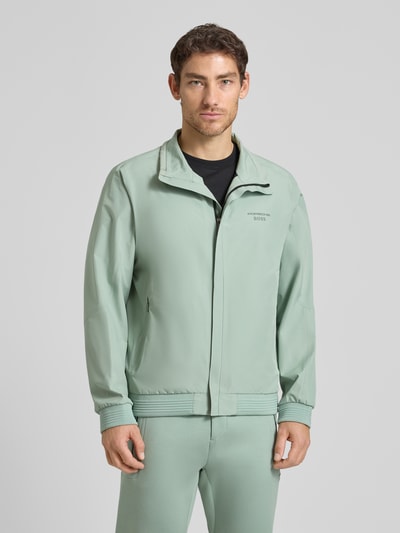 Männermodel trägt Regular Fit Funktionsjacke aus wasserdichtem Material - Porsche x BOSS, Optik: Unifarben, Reißverschlusstaschen, Label-Print, Wärmeisolierung, Stehkragen, Ärmelabschluss und Rumpfabschluss: Gerippt, Ganzkörperansicht von vorne.