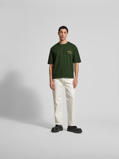 Männermodel trägt Loose Fit T-Shirt aus reiner Baumwolle von Dsquared2 in Dunkelgrün mit Label-Print, Kurzärmelig, Rundhalsausschnitt, Herren T-Shirt, Rückenlänge 68 cm bei Größe M, Ganzkörperansicht von vorne.