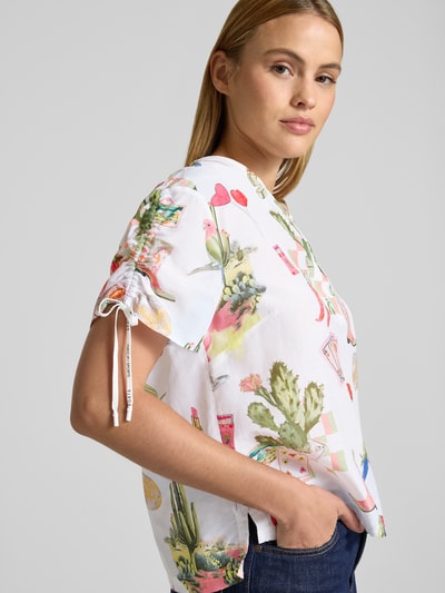 Frauenmodel trägt Regular Fit Bluse im Allover-Look von Marc Cain, Baumwoll-Viskose-Mix, bunte Muster, Ärmel mit Kordelzug, Nahaufnahme Oberkörper.