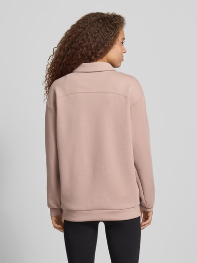 Frauenmodel trägt Relaxed Fit Poloshirt mit Lyocell-Anteil von PUMA in sanftem Rosaton, Langärmelig, Elastischer-Material-Mix, Ganzkörperansicht Rückansicht.