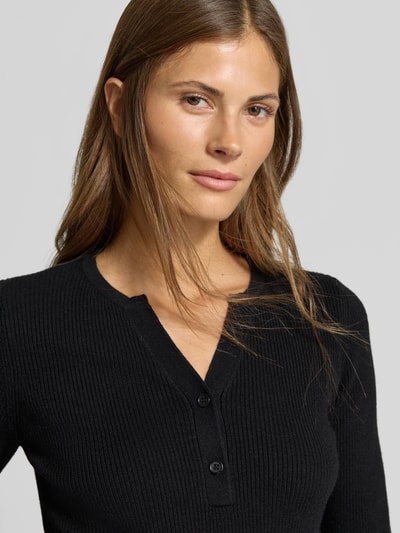 Frauenmodel trägt Slim Fit Longsleeve in Strick-Optik von MYON, Henley-Ausschnitt, schwarze Farbe, Nahaufnahme Oberkörper.