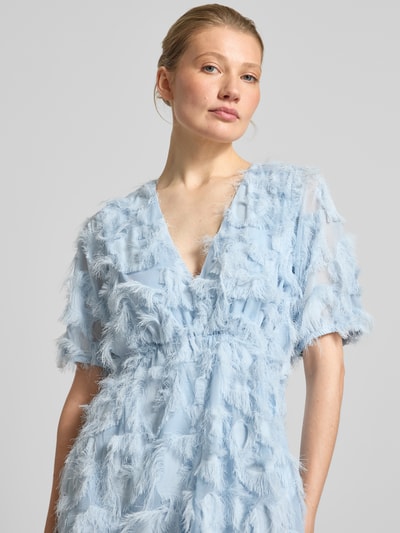 Frauenmodel trägt Cocktailkleid mit Fransen Modell 'PAZYLLA' von YAS in Hellblau, V-Ausschnitt, Midikleid, Nahaufnahme Oberkörper.
