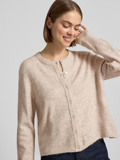 Frauenmodel trägt Loose Fit Strickjacke mit Rundhalsausschnitt Modell 'SIMONI' von ONLY, beige meliert, weiche Textur, Nahaufnahme Oberkörper, Damen Strickjacke von ONLY