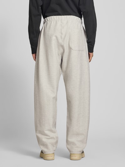 Mannenmodel draagt Sweatpants aus Baumwoll-Mix van Kenzo in lichtbeige met steekzakken en labelprint, los model, mix van katoen en elastaan, bandwijdte maat M 37 cm, binnenbeenlengte maat M 81 cm, geheelopname achterkant.