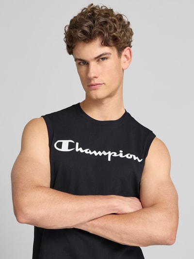Männermodel trägt Top mit Logo und Rundhalsausschnitt von CHAMPION, schwarzer Baumwoll-Mix, Regular-Fit, Nahaufnahme Oberkörper.