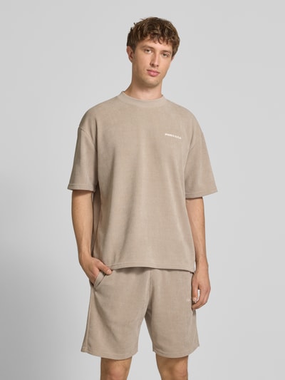 Männermodel trägt Oversized T-Shirt mit Logo-Stitching Modell 'Lagos' von Pegador aus Elastischer-Material-Mix in Beige, Oversized-Fit, Rückenlänge bei Größe M: 65 cm, Ganzkörperansicht von vorne.