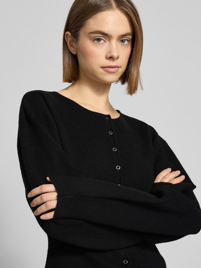 Frauenmodel trägt Regular Fit Strickjacke aus Viskose-Mix in Strick-Optik von Gina Tricot, Rundhalsausschnitt, Nahaufnahme Oberkörper.