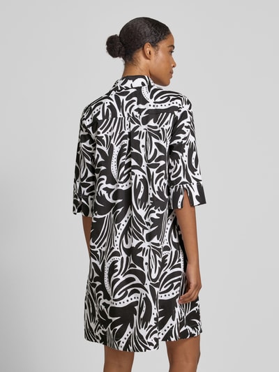 Frauenmodel trägt knielanges Hemdblusenkleid mit verdeckter Knopfleiste von Christian Berg Woman, Reine Baumwolle, Straight Fit, 1/2-Arm, Knielänge, Hemdblusenkragen, Schwarz-Weiß Muster, Ganzkörperansicht Rückansicht.