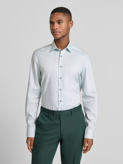 Männermodel trägt Slim Fit Businesshemd aus Baumwoll-Mix mit Kentkragen von OLYMP Level Five, helles Grün, glatte Struktur, Ganzkörperansicht von vorne.