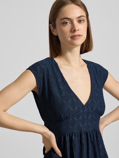 Frauenmodel trägt Kurzes Kleid mit V-Ausschnitt, Lochstickerei und großer Schleife von REVIEW, dunkelblau, Material-Mix mit Stretch-Anteil, A-Linie, Lochstickerei, V-Ausschnitt, Große Schleife, Nahaufnahme Oberkörper.