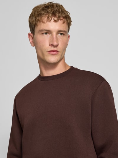 Männermodel trägt Regular Fit Sweatshirt aus Baumwoll-Mix Modell 'CERES' von ONLY & SONS in Dunkelbraun, Nahaufnahme Oberkörper.