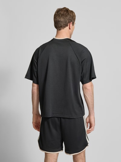Männermodel trägt T-Shirt mit V-Ausschnitt und Logo-Print von adidas Sportswear in Schwarz, lockerer Schnitt, Rückenlänge 67 cm, Ganzkörperansicht Rückansicht.