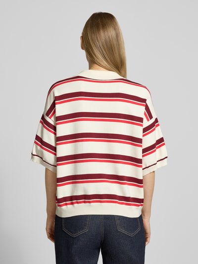Männermodel trägt Relaxed Fit Poloshirt aus mieszanka wiskozy model 'Taia' von Gestuz, kremowe i czerwone pasy, imitacja dzianiny, elastyczne wykończenia, długość tyłu w rozmiarze S: 58 cm, długość rękawów w rozmiarze S: 22 cm, Ganzkörperansicht Rückansicht.