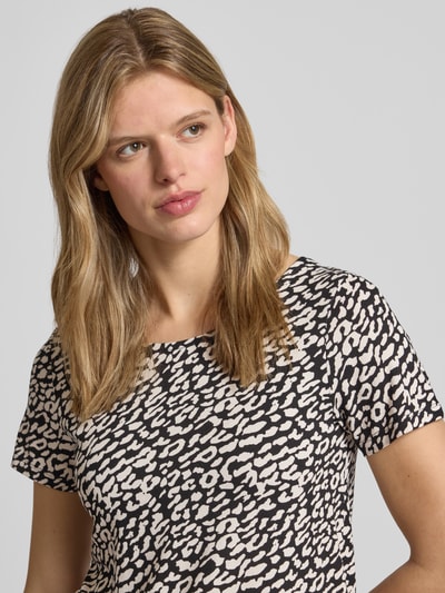 Modelka kobieca nosi Regular Fit T-Shirt aus Viskose-Mix Modell 'BERA' od ONLY z nadrukiem allover, krótki rękaw, detal sznurowania z tyłu, tkanina crêpe, wzór czarno-beżowy, krój regular fit, dekolt typu łódka, materiał wiskozowy mix, Nahaufnahme górnej części ciała.