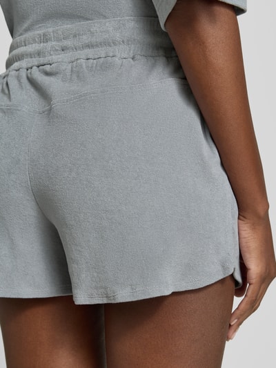 Frauenmodel trägt Straight Fit Shorts mit Tunnelzug Modell 'Saha' von Drykorn, graues Strukturmuster, elastischer Bund, Detailaufnahme Rückansicht.