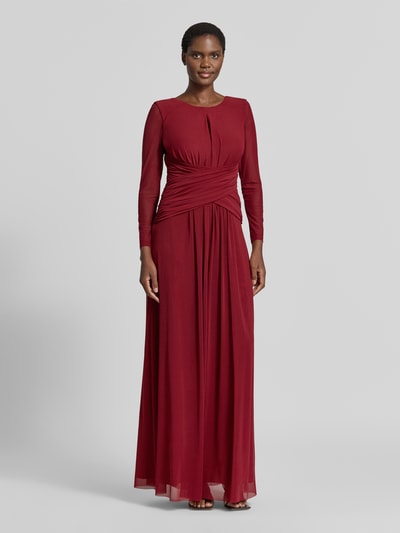 Modelka kobieca nosi 'Abendkleid mit tiefem Rückenausschnitt und Raffungen' od TROYDEN COLLECTION, bordowy szifon, krój slim fit, okrągły dekolt, dekolt typu keyhole, półprzezroczyste długie rękawy, marszczenia, głęboki dekolt na plecach, tylny zamek, długość tyłu w rozmiarze 36: 152 cm, szerokość w rozmiarze 36: 36 cm, długość rękawa w rozmiarze 36: 58 cm, widok całej sylwetki z przodu.