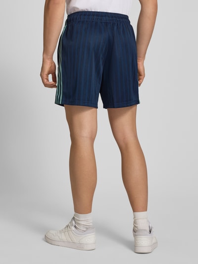 Mężczyznęmodel nosi Loose Fit Trikot-Shorts mit DFB-Applikation von adidas Originals, granatowo-czarny wzór, kontrastowe paski, elastyczny ściągacz, tkanina żakardowa, widok całej sylwetki z tyłu.