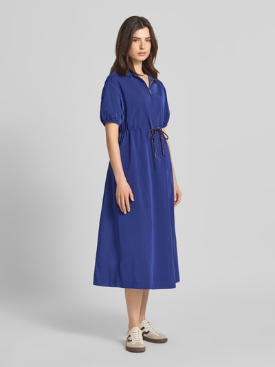 Frauenmodel trägt Midikleid mit kurzem Reißverschluss und Kordelzug an der Taille von Rich & Royal in Blau, taillierter Schnitt, Halbarm, Ganzkörperansicht von vorne.
