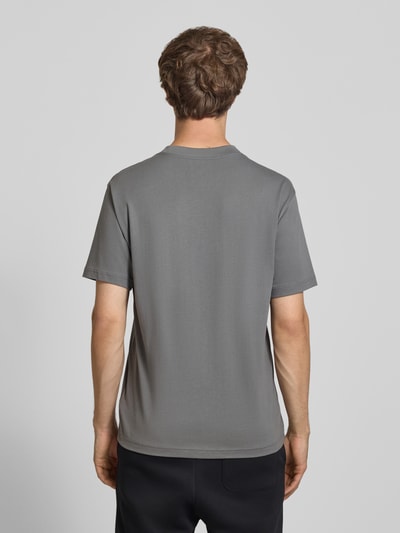 Männermodel trägt T-Shirt mit Logo und Rundhalsausschnitt von New Balance in Grau, reine Baumwolle, Regular Fit, Rückenansicht, Ganzkörperansicht Rückansicht.