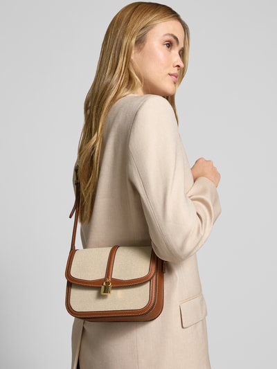 Frauenmodel trägt Crossbody Bag in Flecht-Optik Modell 'Bilmac' von Mango, beige mit braunen Akzenten, Überschlag, Verstellbarer Schulterriemen, Ganzkörperansicht Rückansicht. Hauptfach, Maße: Breite 20 cm, Länge 16 cm, Tiefe 8 cm, Riemenlänge 102 cm.