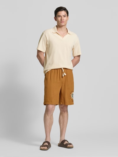 Mężczyzna nosi Relaxed Fit Poloshirt in Pique-Optik od Scotch & Soda, bawełna, krój relaxed fit, kołnierzyk polo, krótki rękaw, długość tyłu w rozmiarze M: 70 cm, kolor jasny, gładka struktura, widok całej sylwetki z przodu