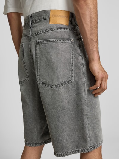 Männermodel trägt Jeansshorts im Used-Look mit Eingrifftaschen von REVIEW, graue Reine Baumwolle, Relaxed-Fit, Ganzkörperansicht Rückansicht.